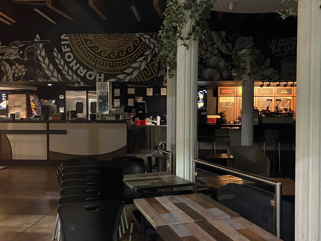 La barra de café de Apolo, entre columnas con enredaderas y el mural de las variedades al fondo