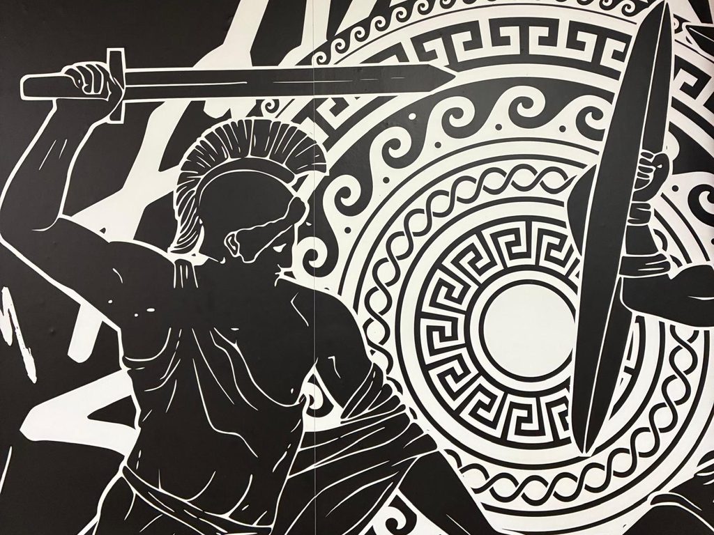 El mural del guerrero griego pintado en blanco y negro sobre la pared del salón de Apolo
