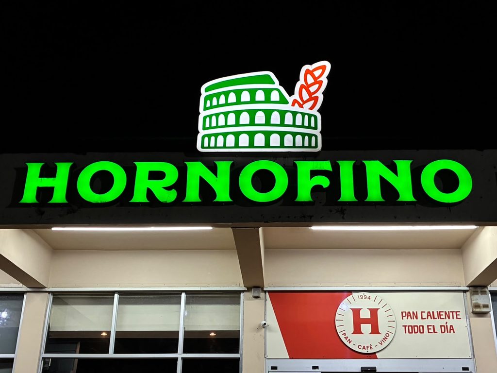 El rótulo verde de HORNOFINO encendido de noche sobre la entrada del local de Apolo