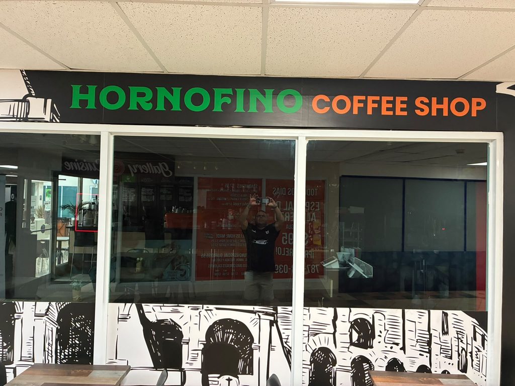 El frente del local, con el rótulo verde y anaranjado de HORNOFINO Coffee Shop sobre las vitrinas