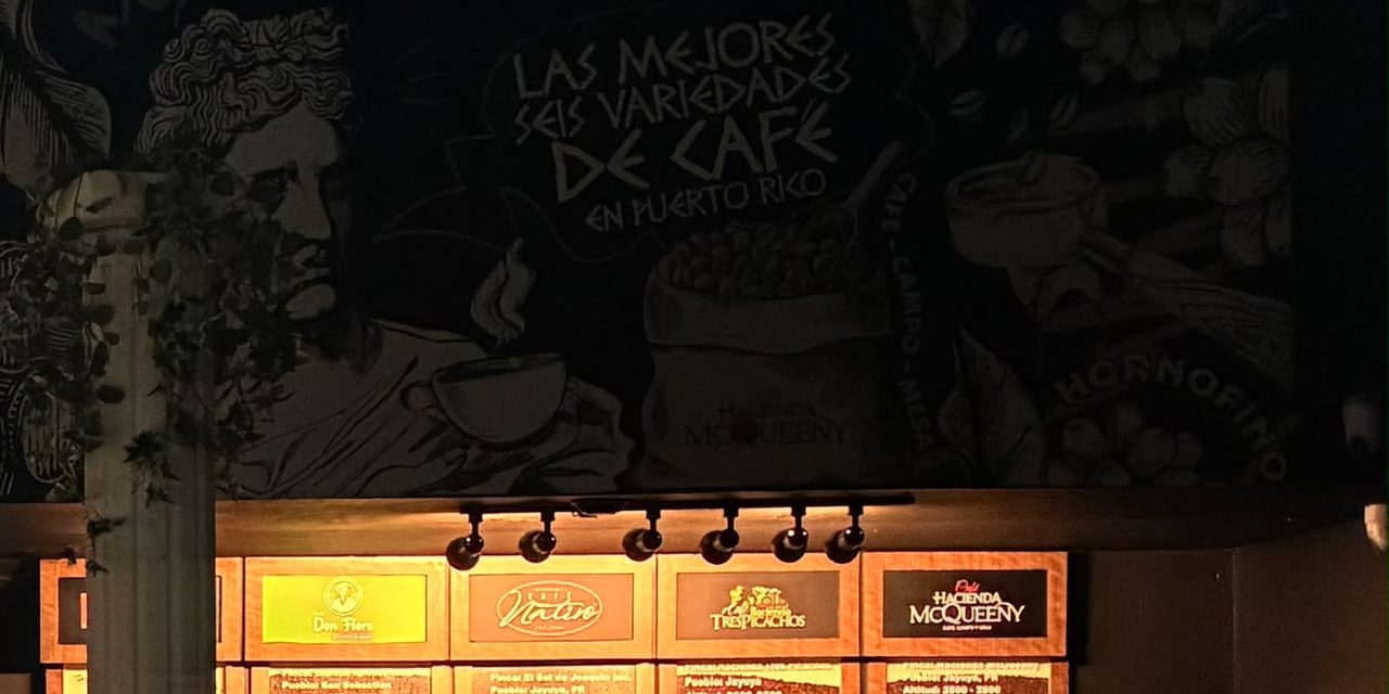 Pared pintada a mano en HORNOFINO Apolo, en Guaynabo, con el letrero «Las mejores seis variedades de café en Puerto Rico» sobre la barra de catación; el último tablero es el de Hacienda McQueeny
