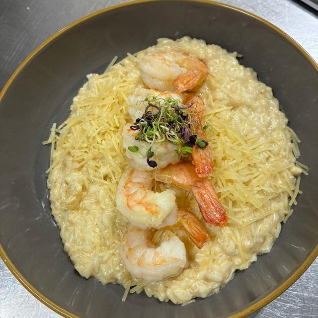 Camarones al ajillo sobre arroz, con queso rallado y cebollín